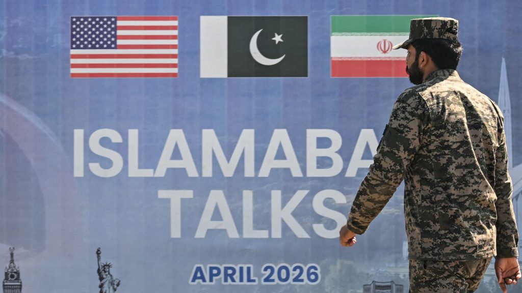 A Pakistani Ranger walks past a billboard for the U.S.-Iran peace talks in Islamabad on April 12, 2026.